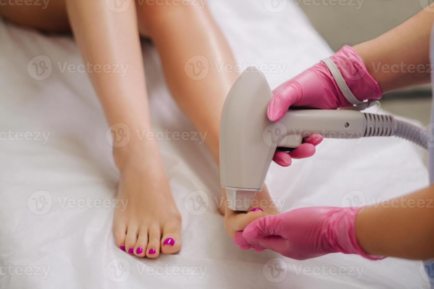 A cosmetologist performs a laser hair removal procedure in the office photo