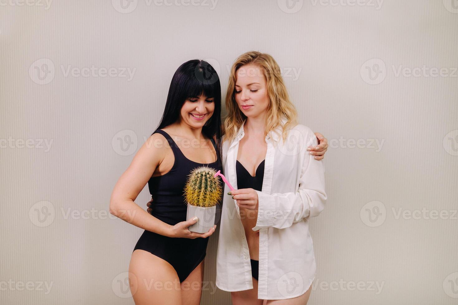 Cactus concept. Unshaven body . One girl is holding a cactus in her hands, and the second girl is holding a razor. Symbol of unshaven body parts photo