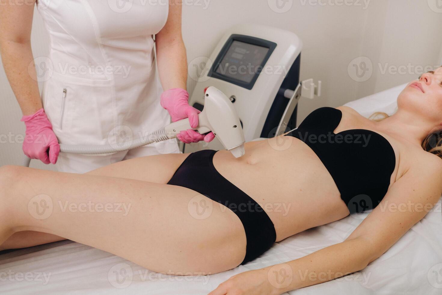 A girl in black underwear gets laser hair removal on her body in the salon photo