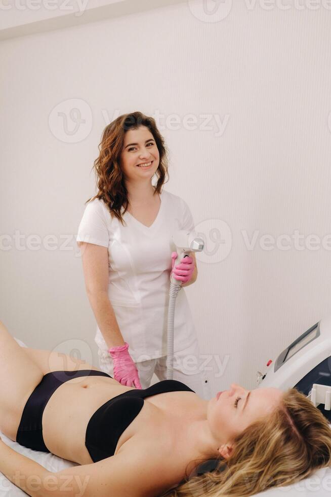 A cosmetologist performs a laser hair removal procedure in the office photo