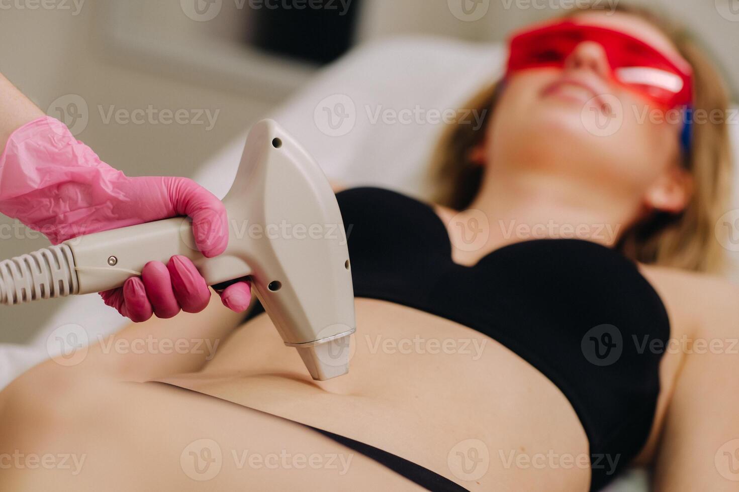 A girl in black underwear gets laser hair removal on her body in the salon photo