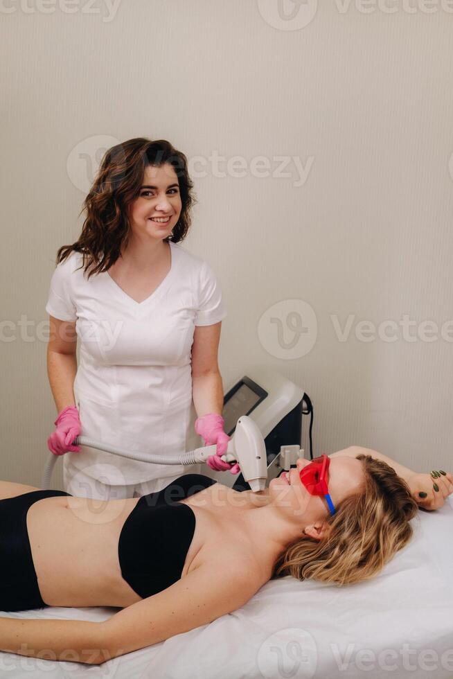 A doctor does laser hair removal for a client of unwanted facial hair in a beauty salon photo