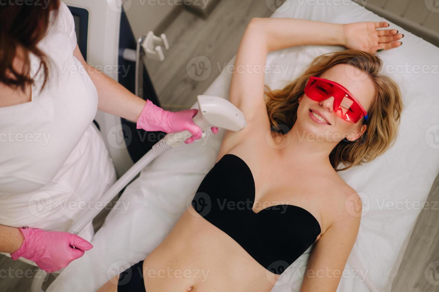 A girl in black underwear gets laser hair removal on her body in the salon photo