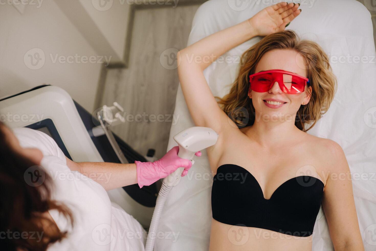 A girl in black underwear gets laser hair removal on her body in the salon photo