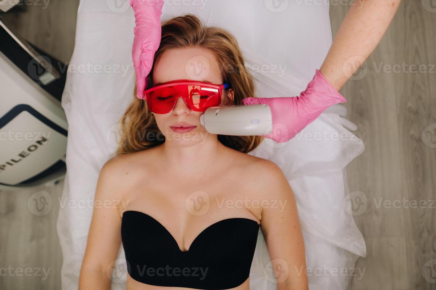 A girl in black underwear gets laser hair removal on her body in the salon photo