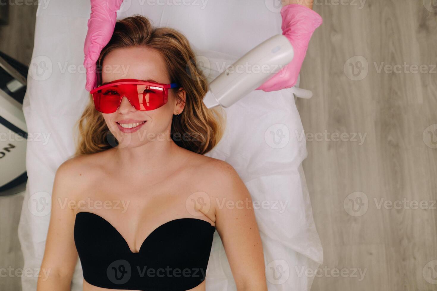 A girl in black underwear gets laser hair removal on her body in the salon photo