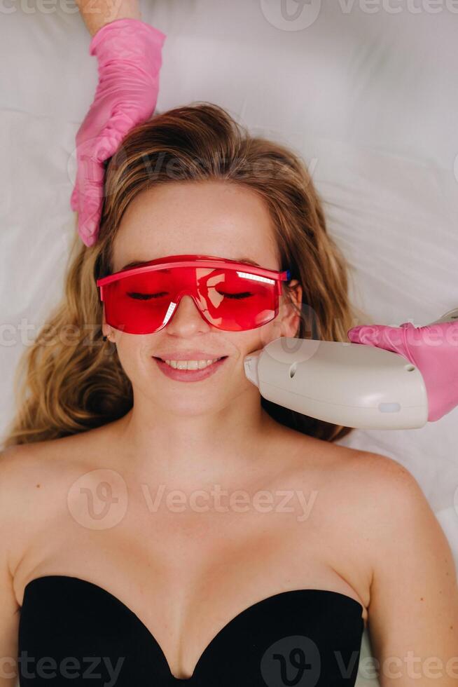 A girl in black underwear gets laser hair removal on her body in the salon photo