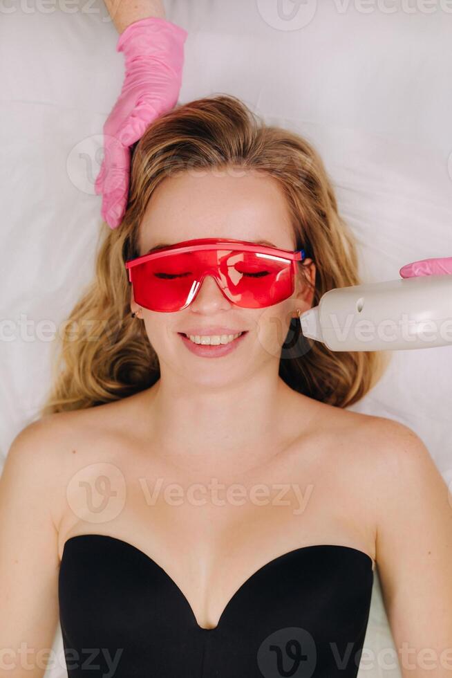 A girl in black underwear gets laser hair removal on her body in the salon photo
