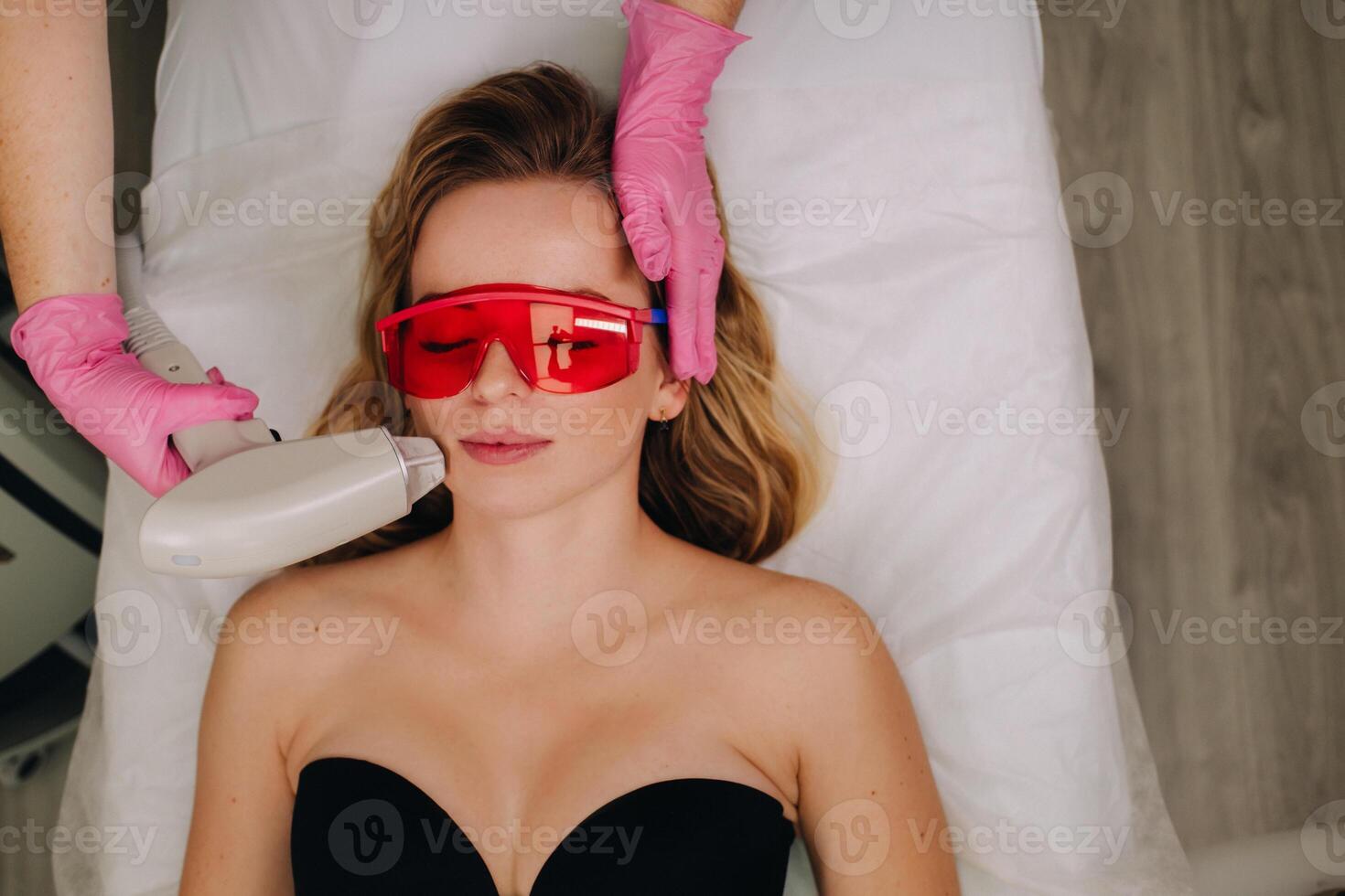 A girl in black underwear gets laser hair removal on her body in the salon photo
