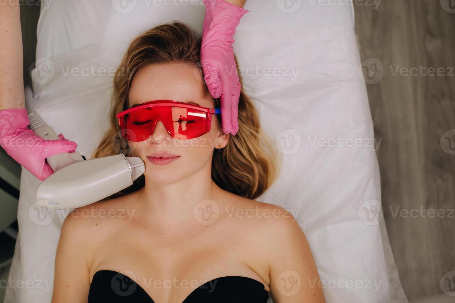 A girl in black underwear gets laser hair removal on her body in the salon photo