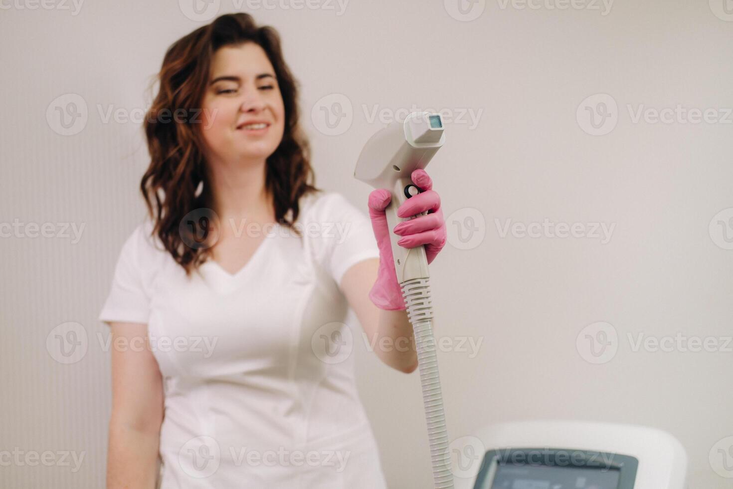 Portrait of the master of laser hair removal. A woman in a white coat holds a laser hair removal device in her hands photo