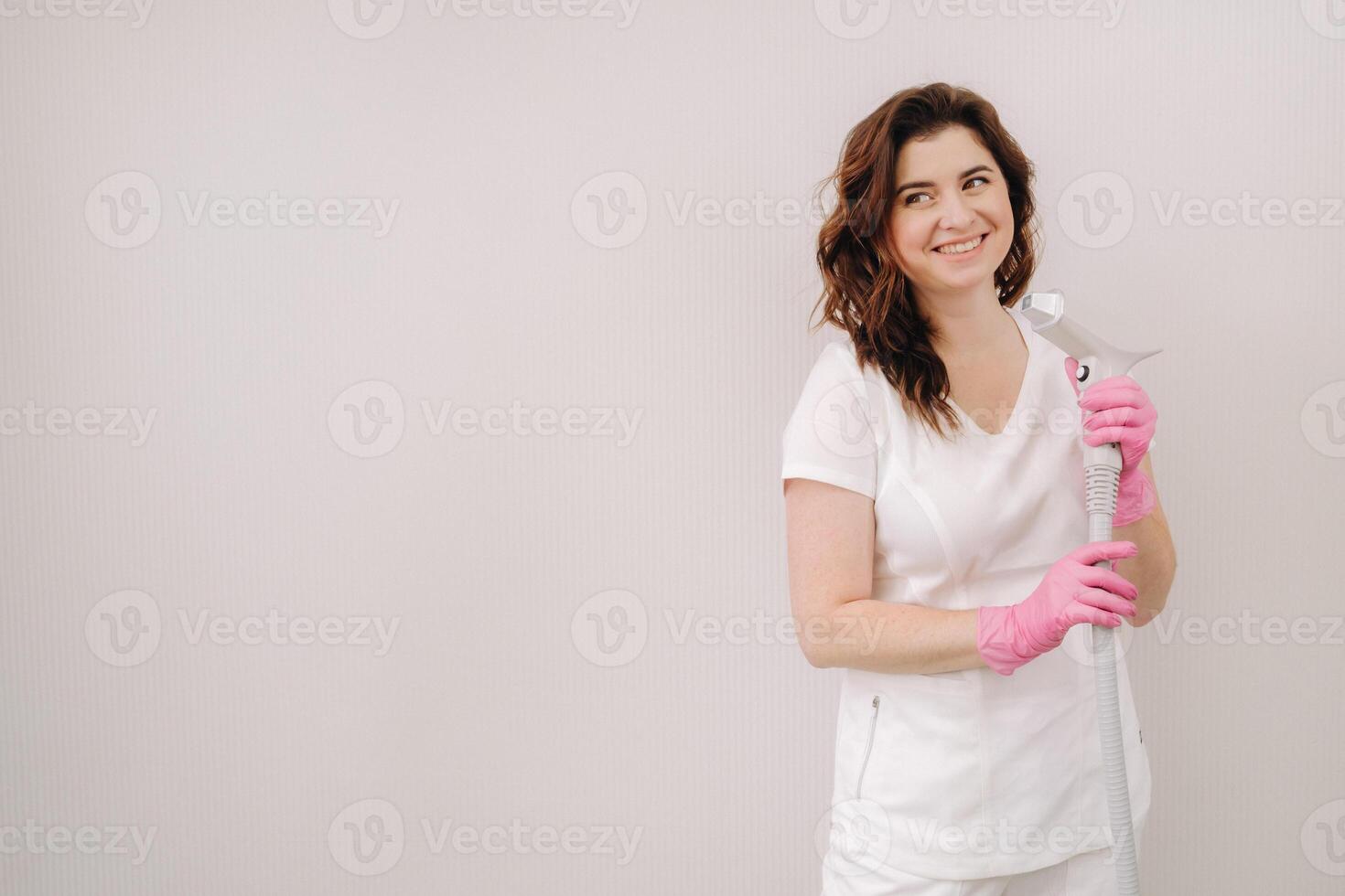 Portrait of the master of laser hair removal. A woman in a white coat holds a laser hair removal device in her hands photo