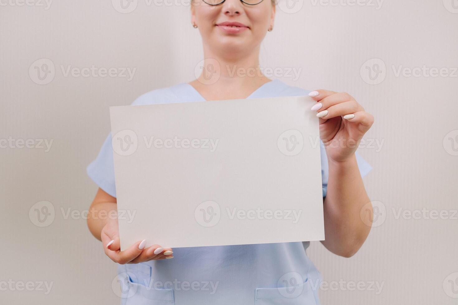 Portrait of a female doctor in a blue robe holding a white blank sheet photo