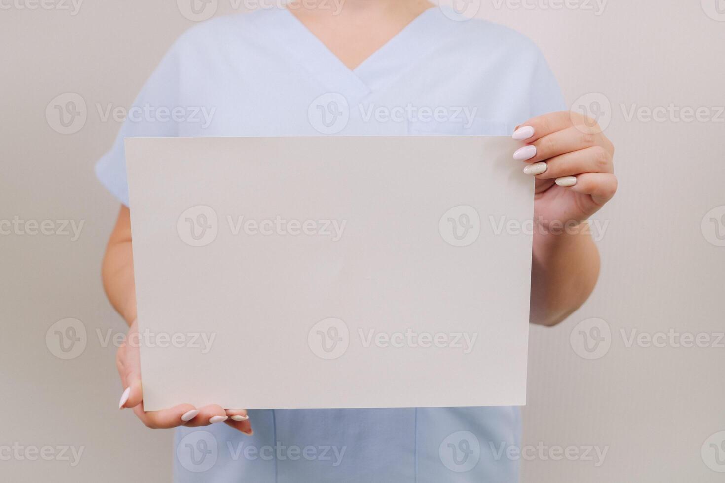 Portrait of a female doctor in a blue robe holding a white blank sheet photo