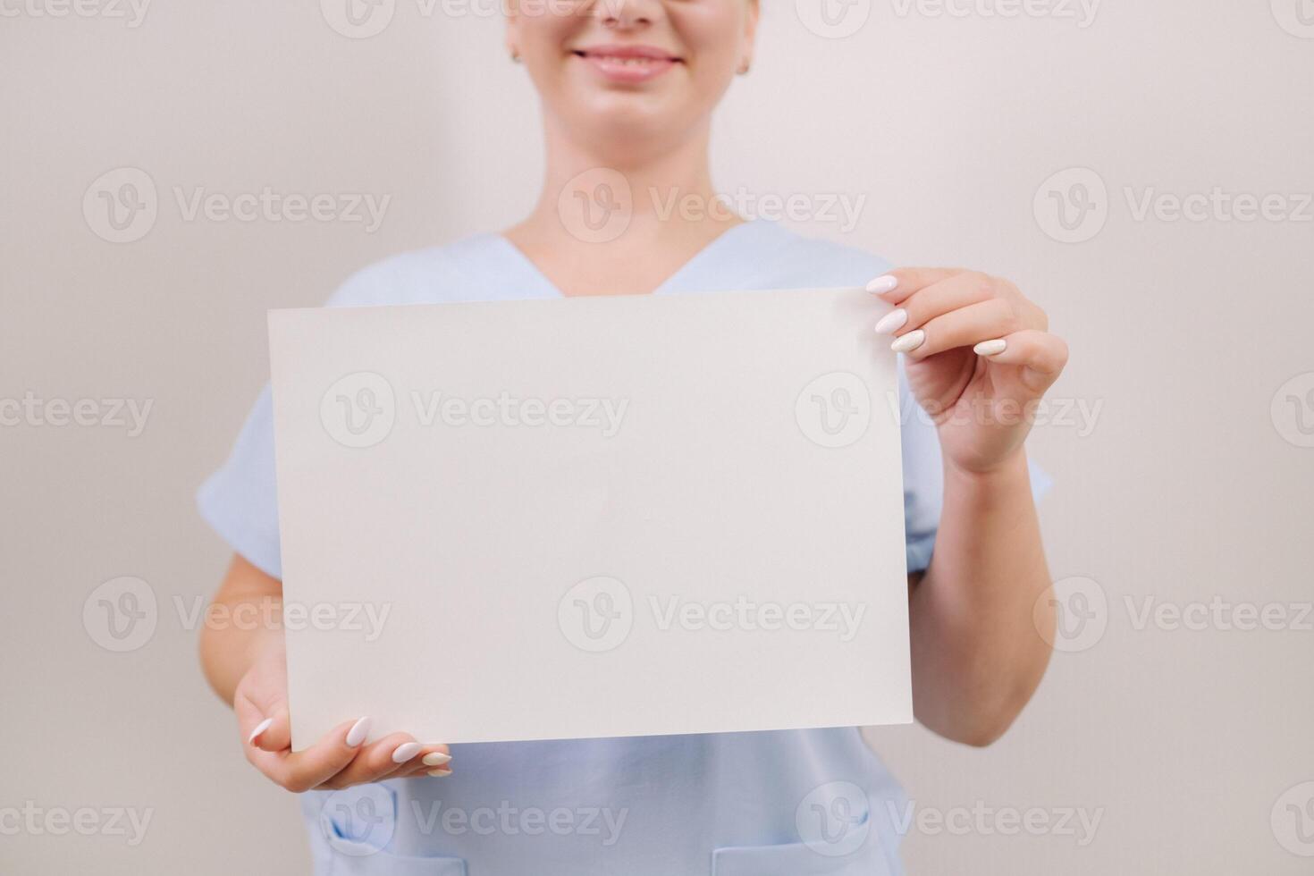 Portrait of a female doctor in a blue robe holding a white blank sheet photo
