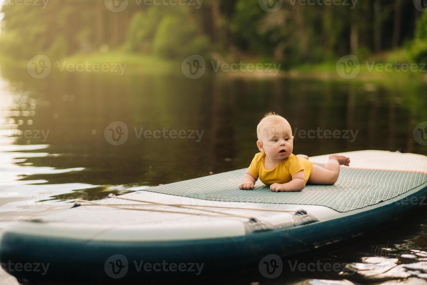 The child lies floating on the water on a large sup board. Water sports photo