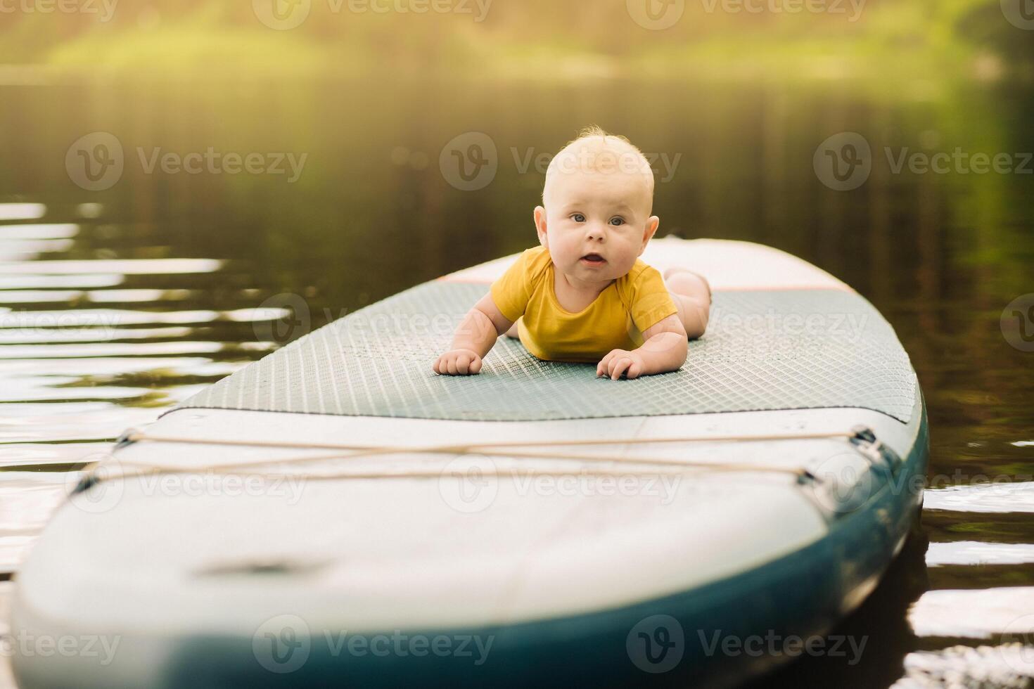 The child lies floating on the water on a large sup board. Water sports photo