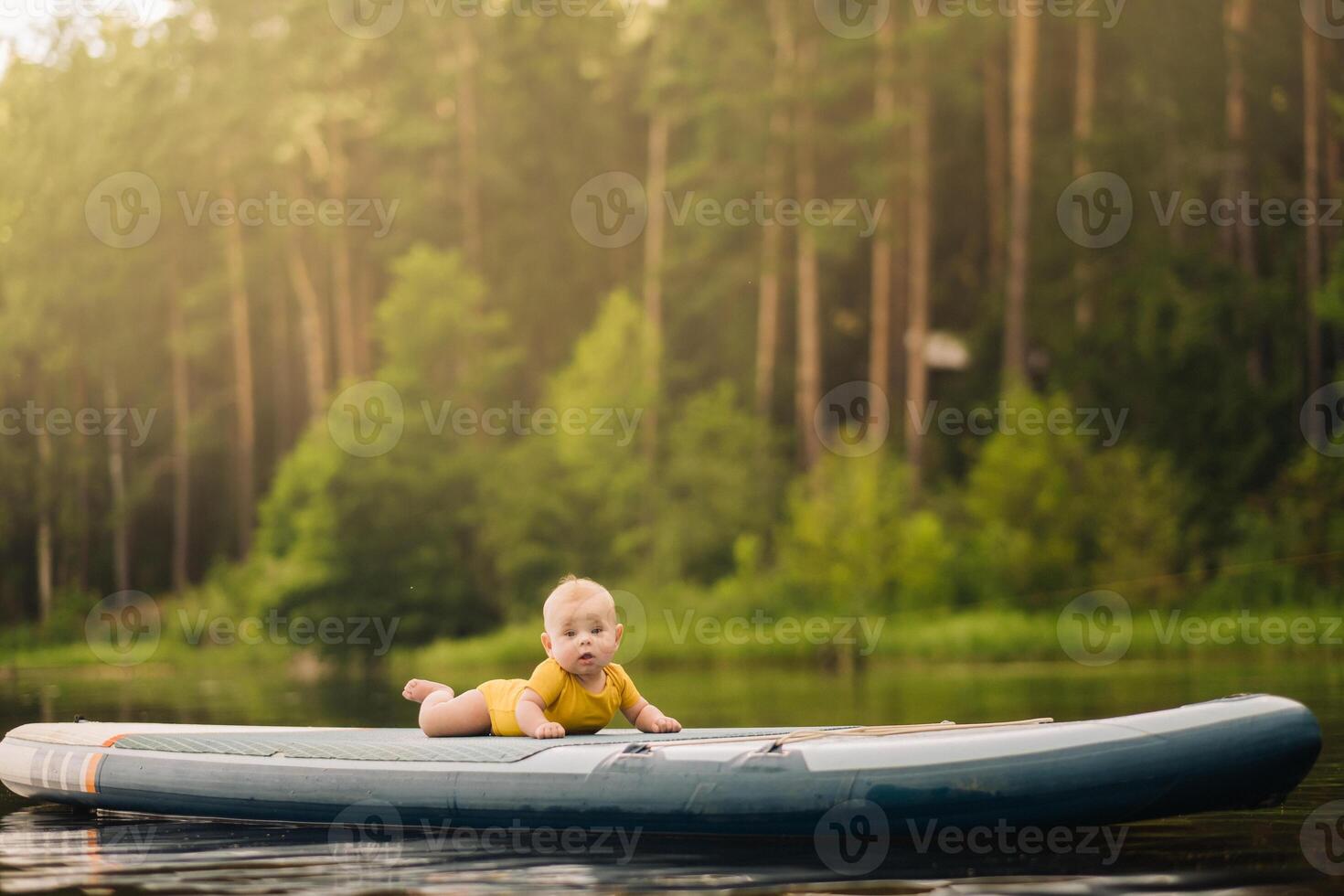 The child lies floating on the water on a large sup board. Water sports photo