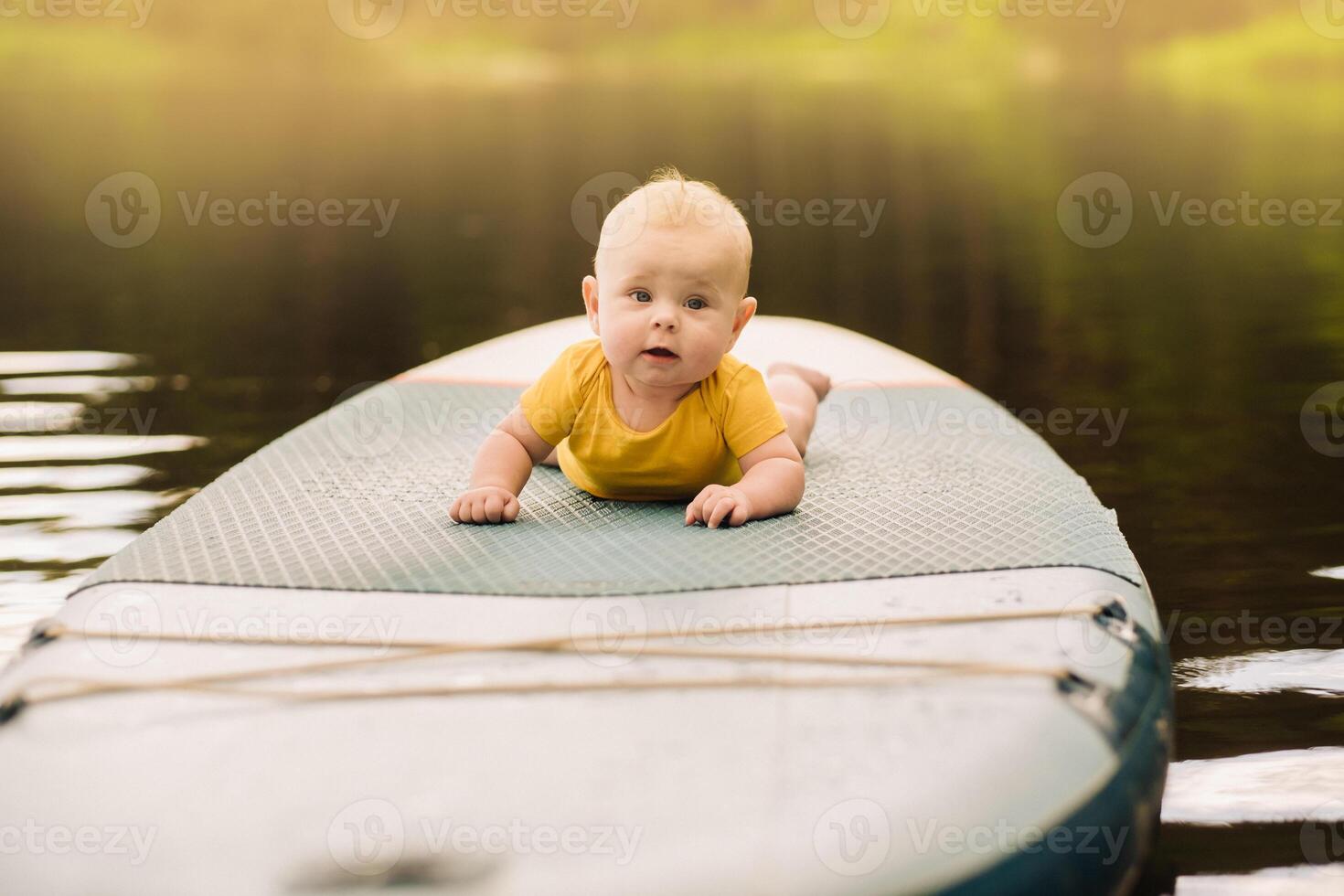 The child lies floating on the water on a large sup board. Water sports photo