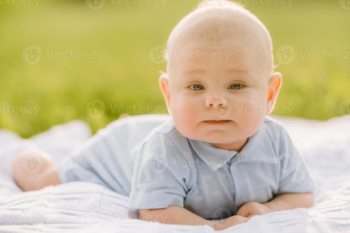 Cute happy toddler lying on a blanket on the grass outdoors in summer photo
