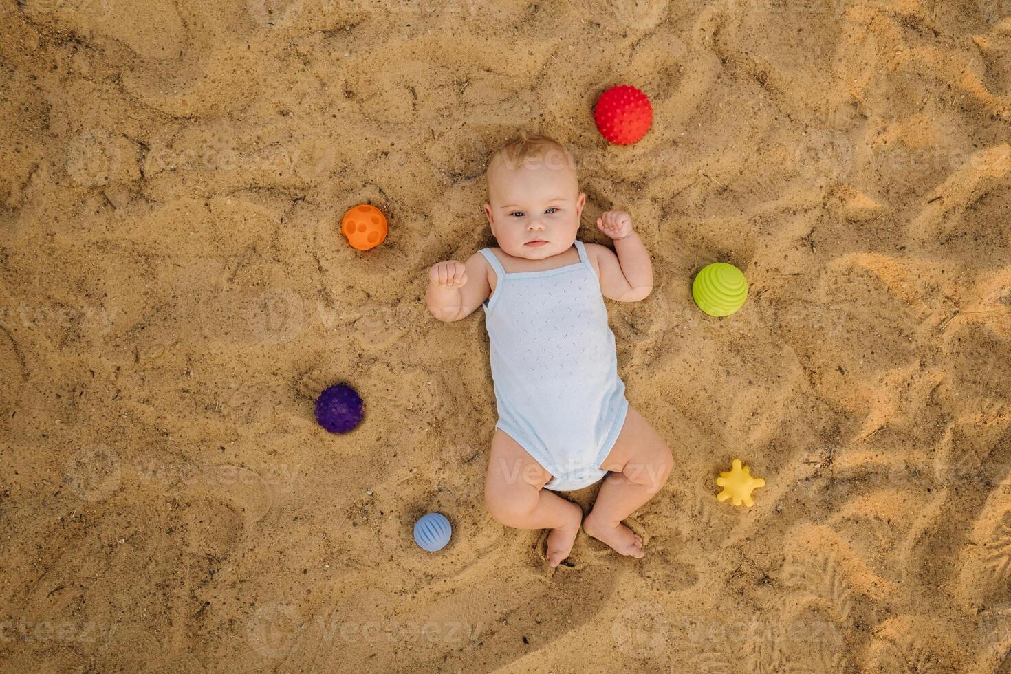 Top view of a happy little boy lying on a sandy beach photo