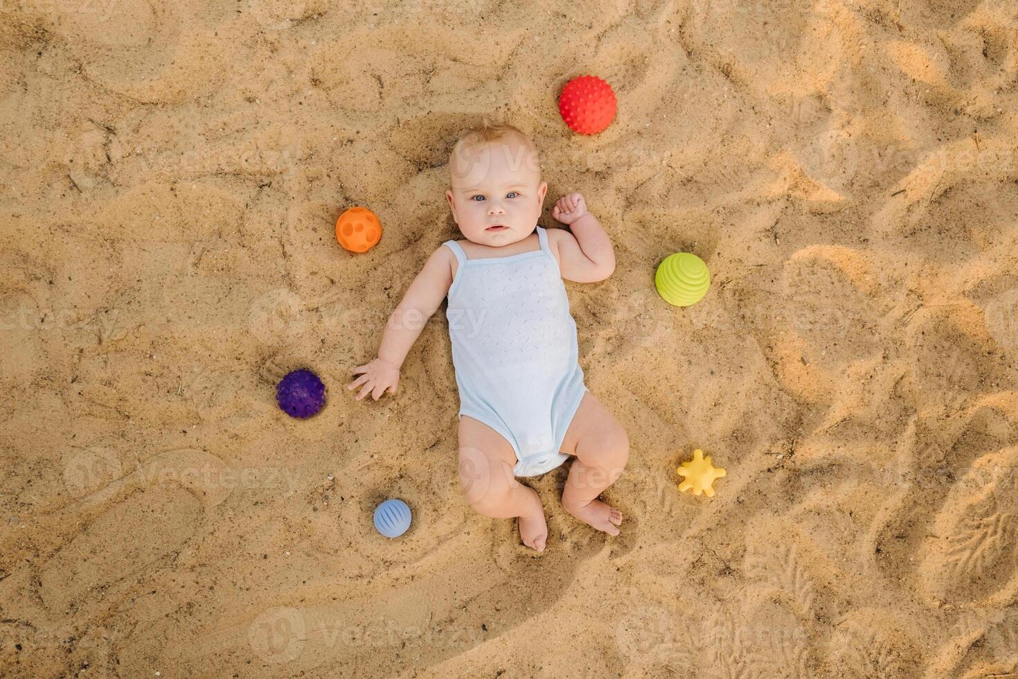 Top view of a happy little boy lying on a sandy beach photo