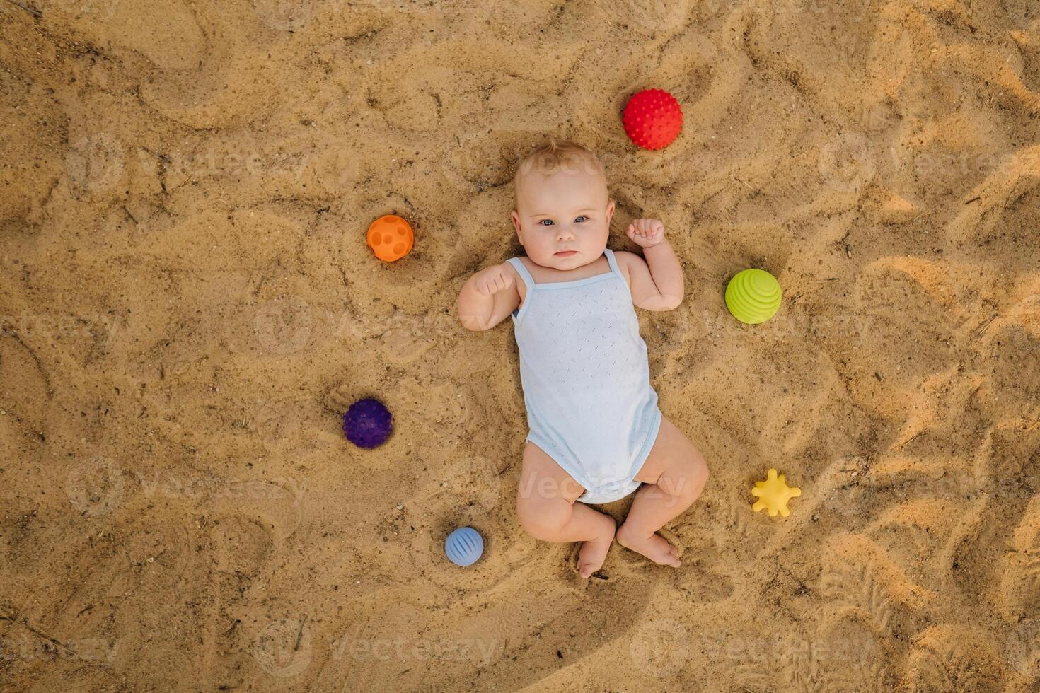 Top view of a happy little boy lying on a sandy beach photo