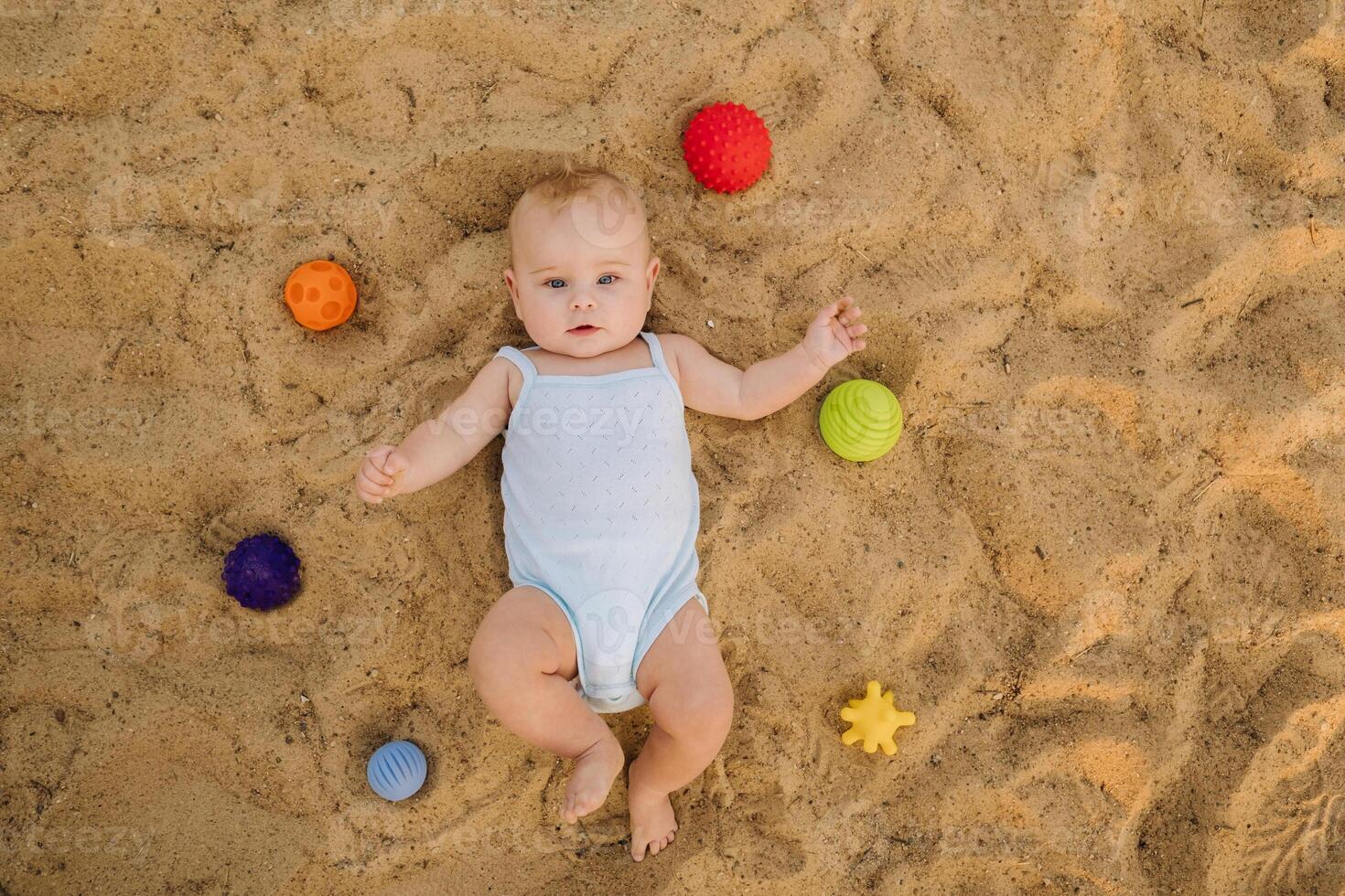 Top view of a happy little boy lying on a sandy beach photo