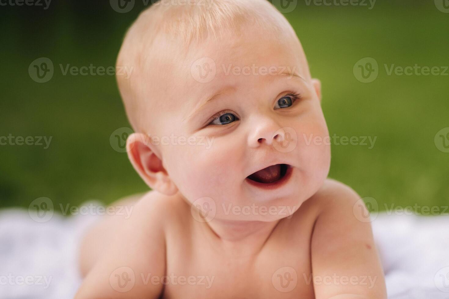 Cute happy toddler lying on a blanket on the grass outdoors in summer photo
