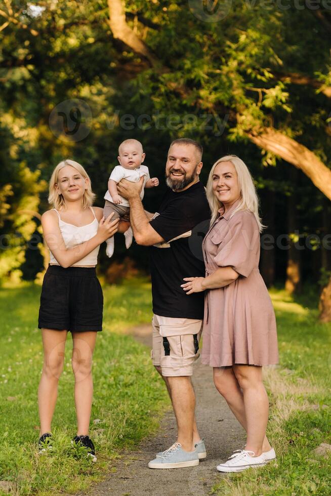 Happy family in the park of four people in the summer in the park in nature photo