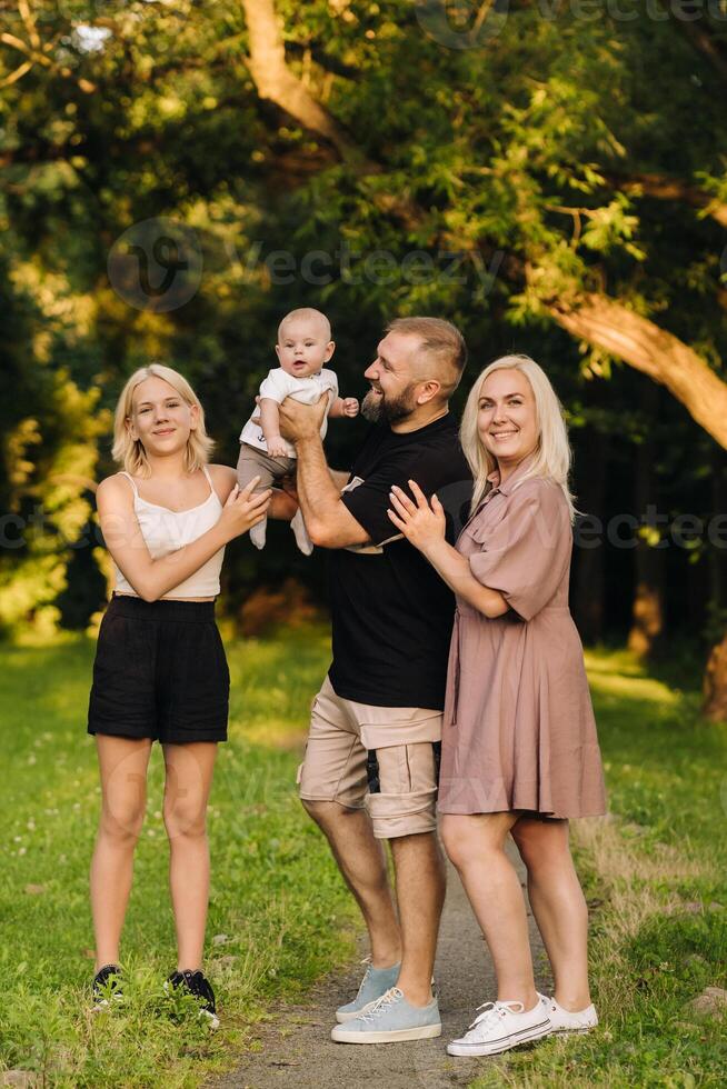Happy family in the park of four people in the summer in the park in nature photo