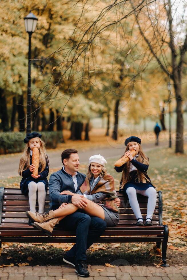 A large family is sitting on a bench in an autumn park. Happy people in the autumn park photo