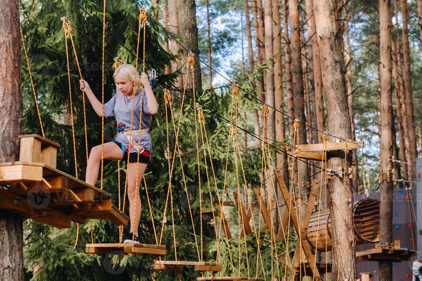 A girl passes an obstacle in a rope town. A girl in a forest rope park photo