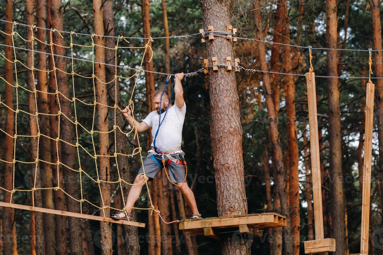 A man overcomes an obstacle in a rope town. A man in a forest rope park photo