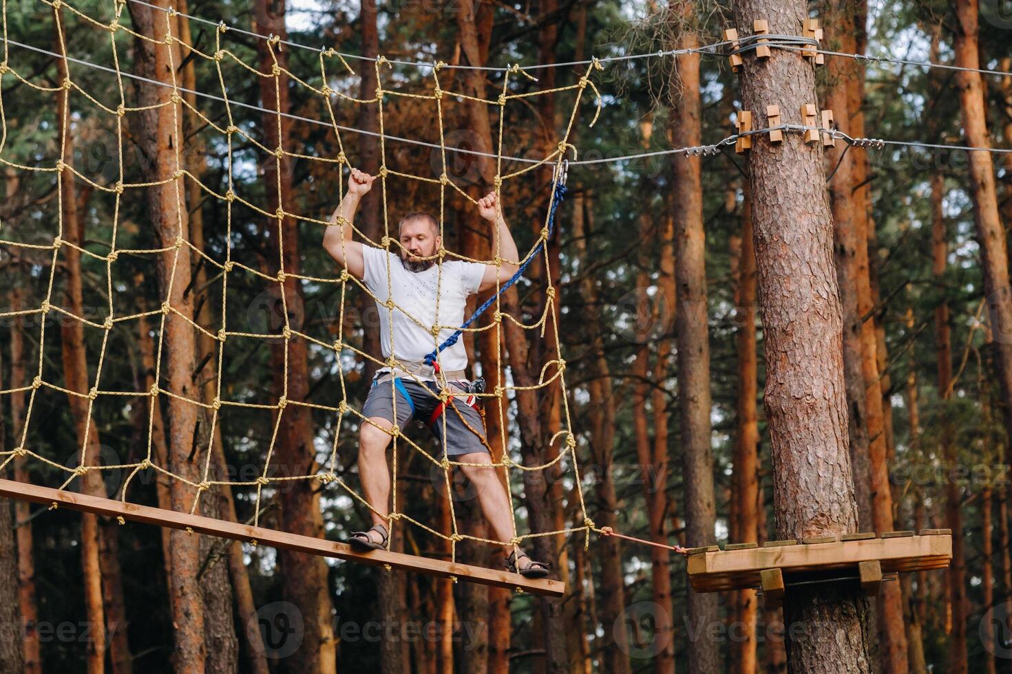 A man overcomes an obstacle in a rope town. A man in a forest rope park photo