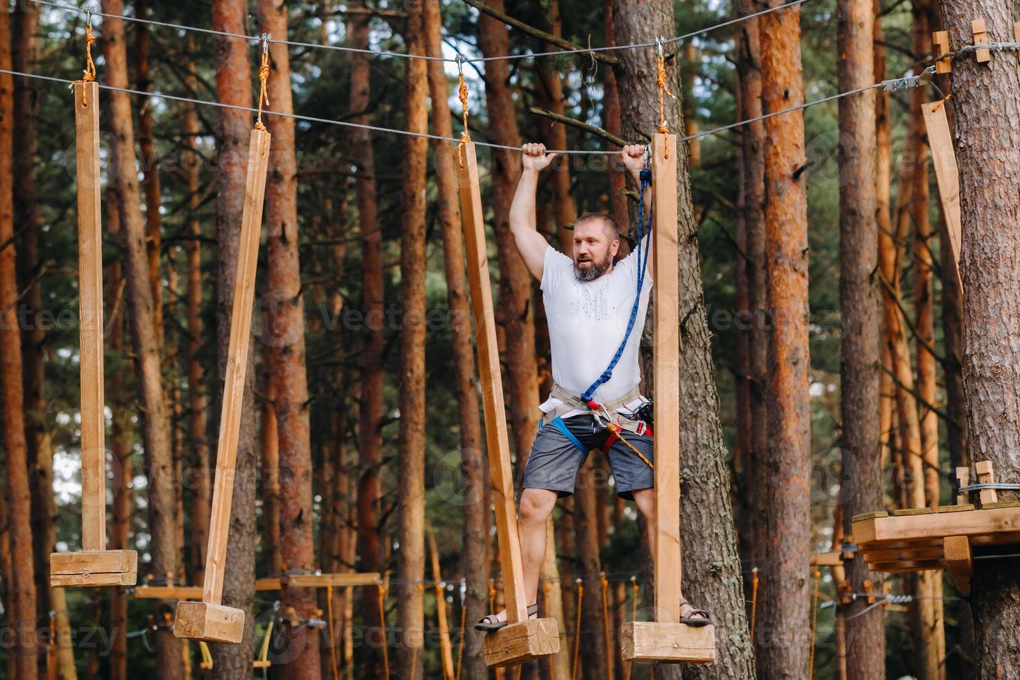 A man overcomes an obstacle in a rope town. A man in a forest rope park photo