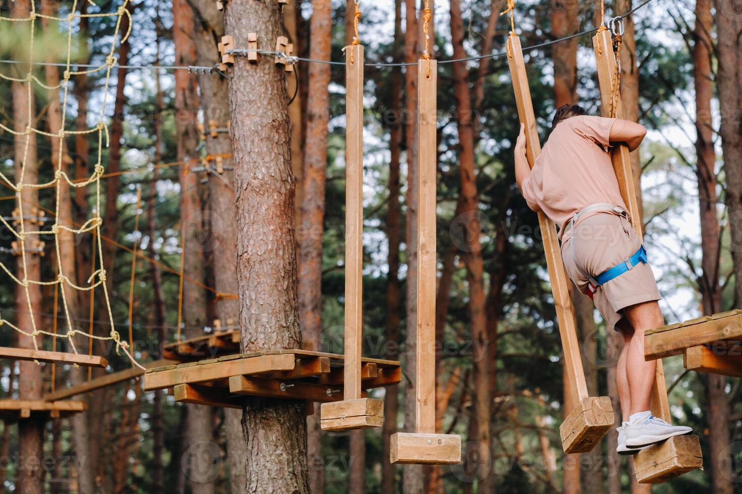 A man overcomes an obstacle in a rope town. A man in a forest rope park photo