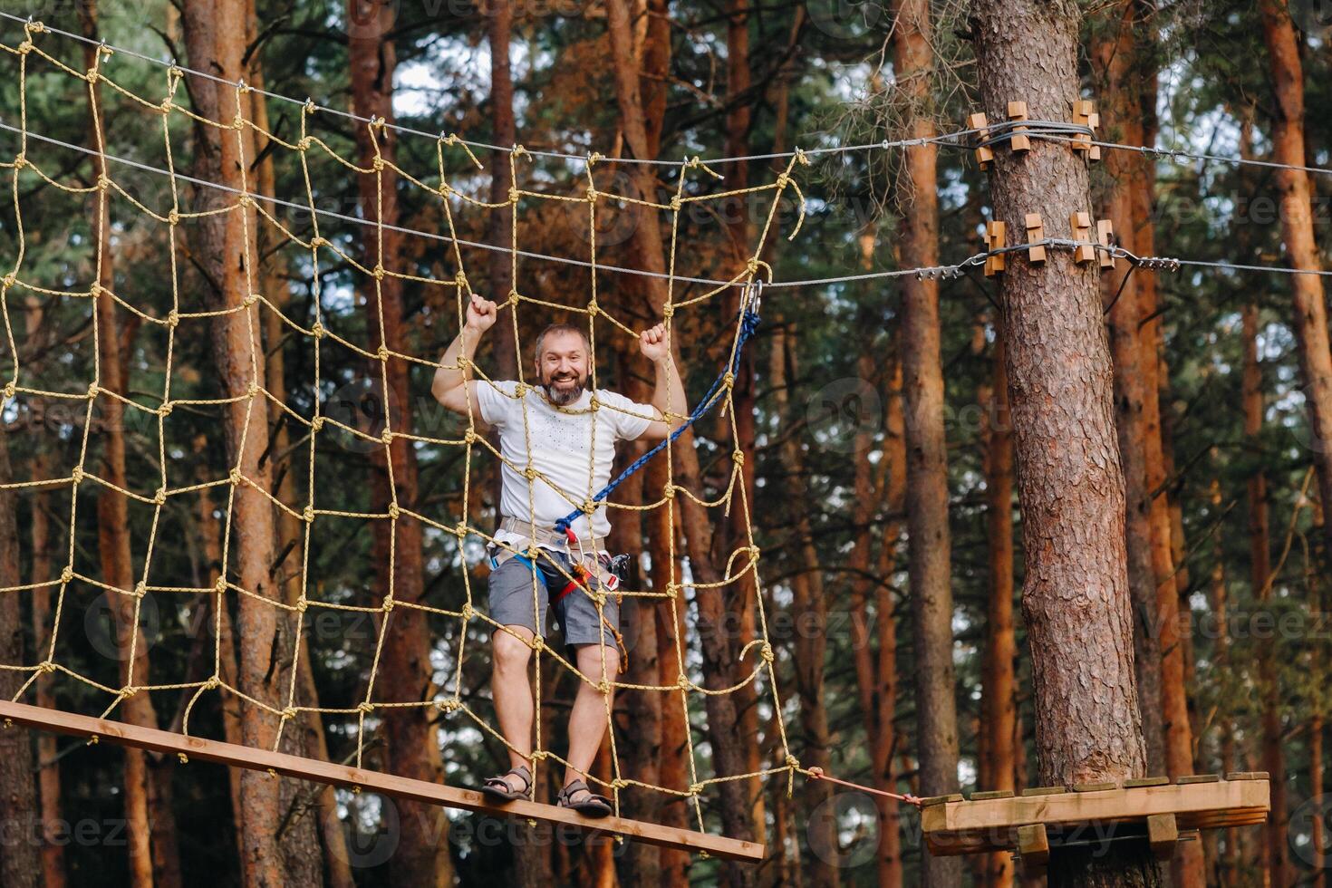 A man overcomes an obstacle in a rope town. A man in a forest rope park photo