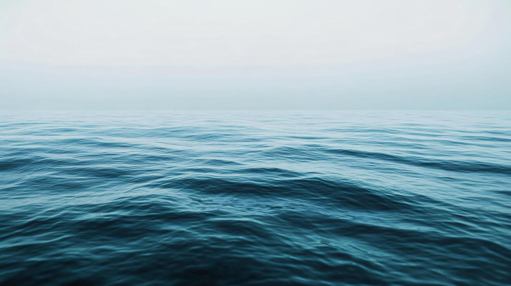 The ocean is calm and peaceful, with no signs of life. The water is a deep blue color, and the sky is a light gray. The scene is serene and tranquil, with no distractions or disturbances photo