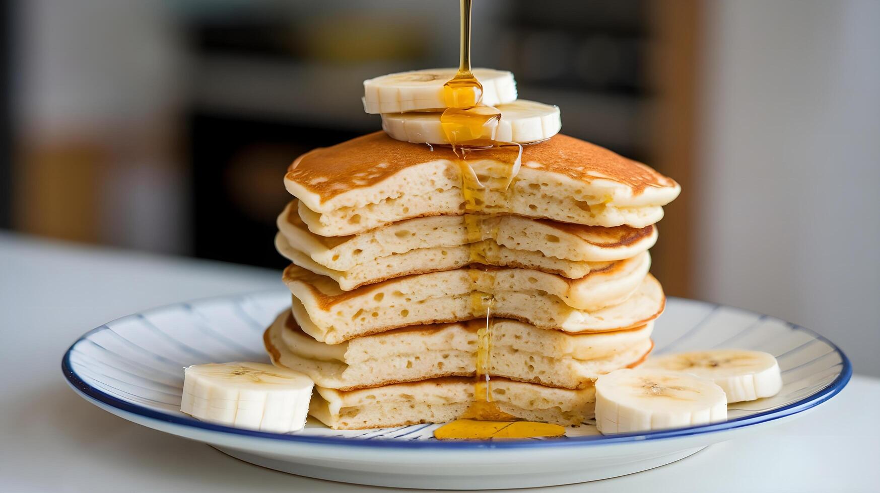 A stack of pancakes with bananas and syrup being poured over them photo