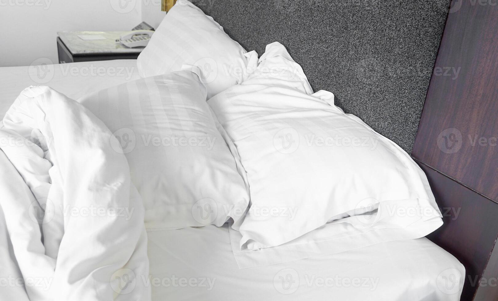 The bed is unmade and the sheets are wrinkled. photo