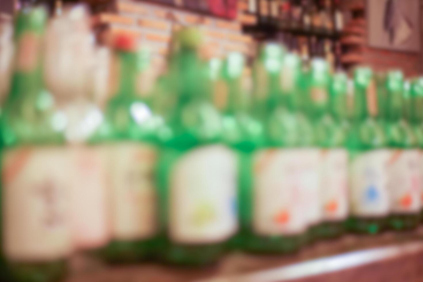 Blurred image of Soju or Korean burned liquor in green glass bottles on the countertop at the pub or restaurant for background. photo