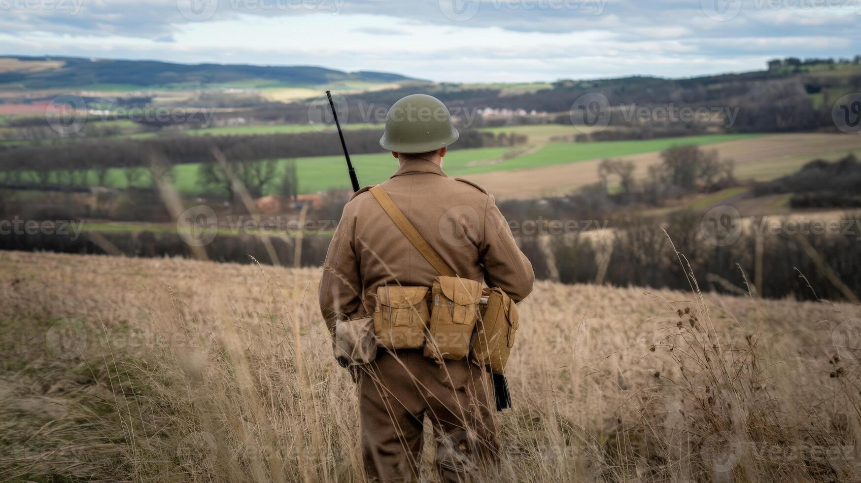 A soldier in a field with a rifle and a hat photo