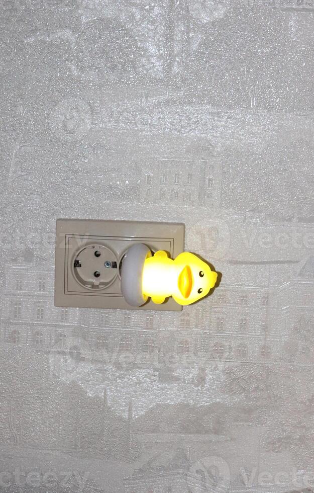 Children's night light plastic switched on lamp yellow duckling, inserted into the socket photo