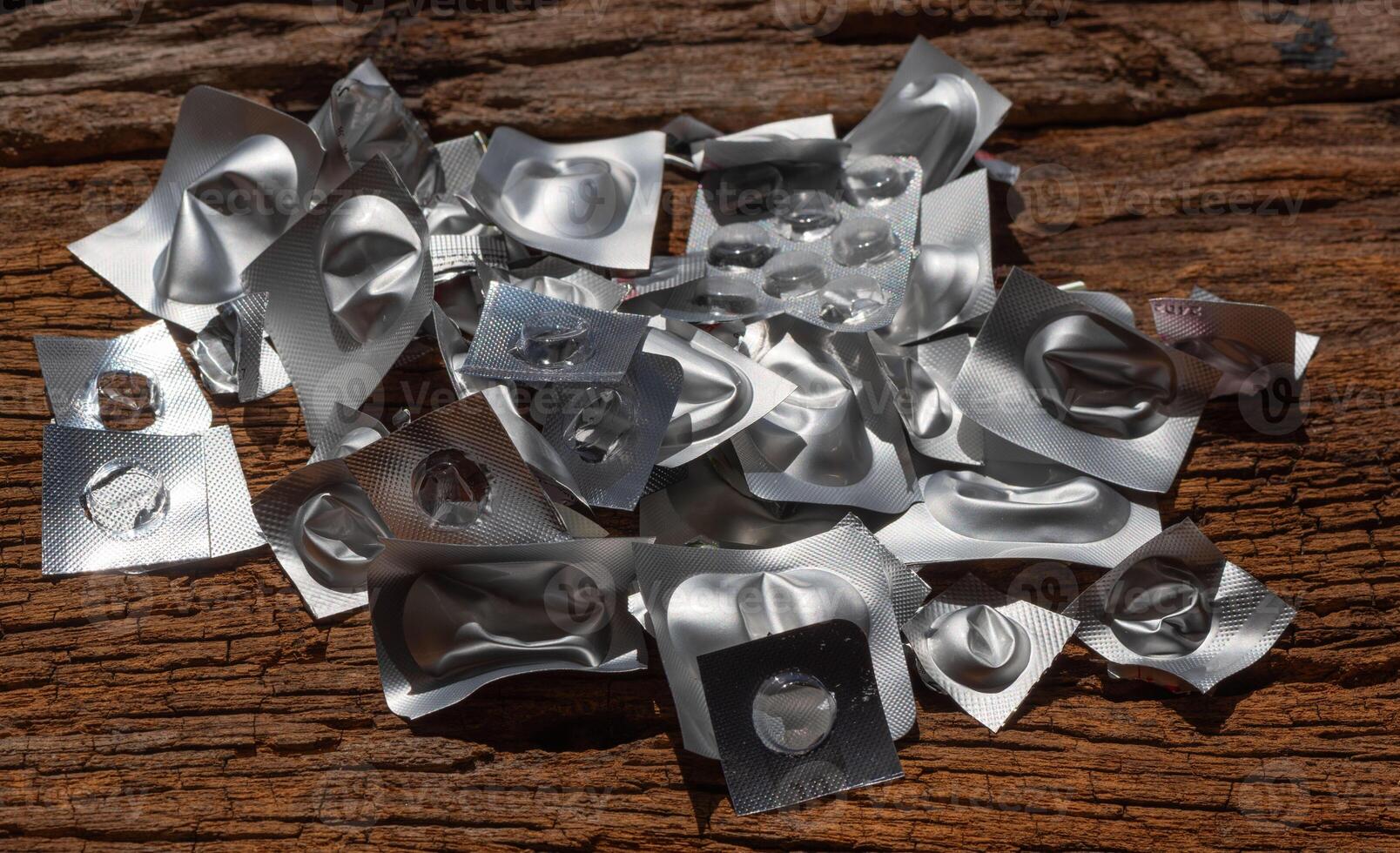 Orphan waste recycling concept. Empty blister packs scattered on wooden surface photo