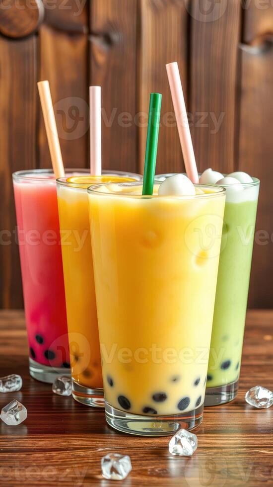 Colorful bubble teas with different flavors served in clear glasses on a wooden table photo