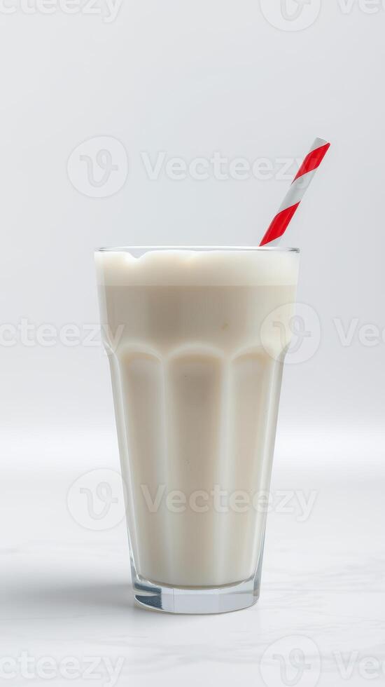 cremoso malteada en un alto vaso con un a rayas Paja en un ligero antecedentes foto