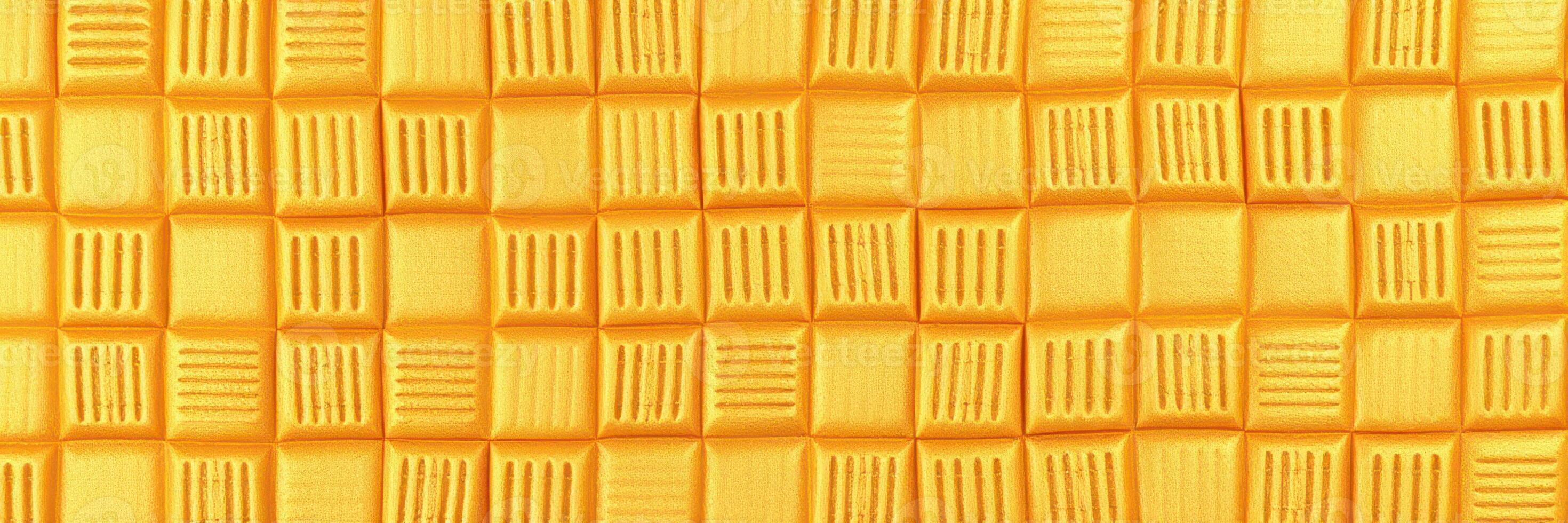 Bright yellow textured surface resembling a checkerboard pattern created with clay or similar material photo