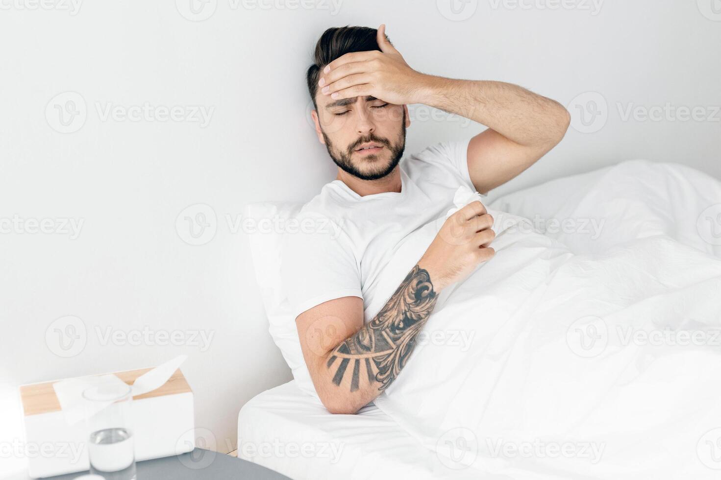 Feeling unwell. Ill man having severe headache suffering from pain and touching forehead, sitting in bed at home, copy space. Migraine during influenza and cold concept photo