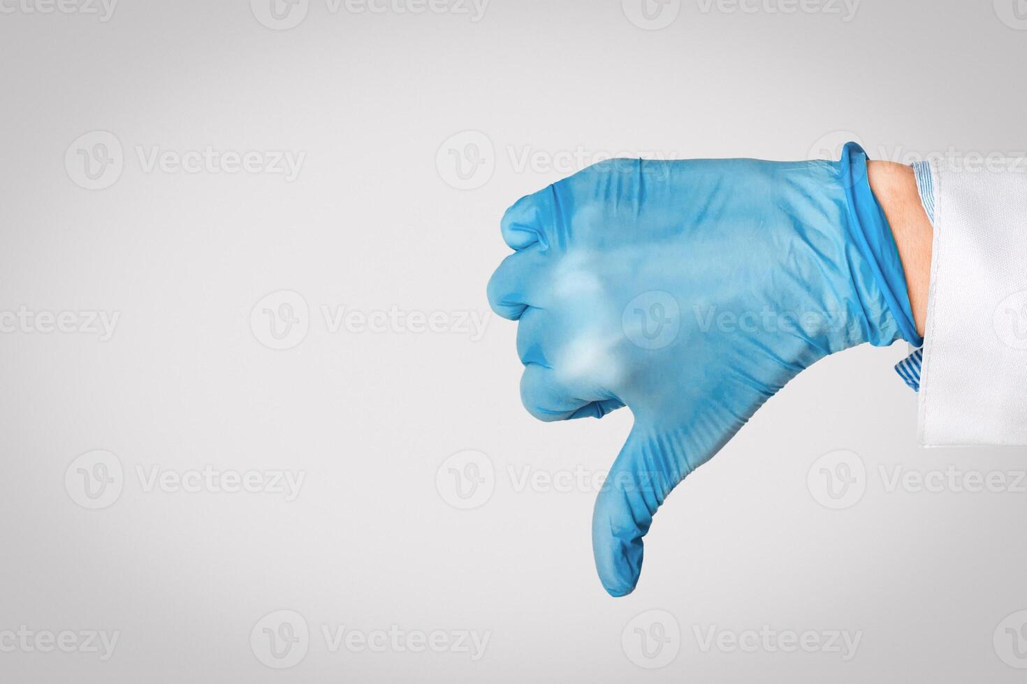 Hand in medical glove shows dislike sign, free space photo